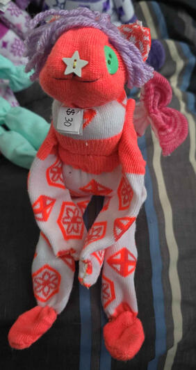 Blood-orange, purple, fuchsia and white doll with sparkly purple hair.