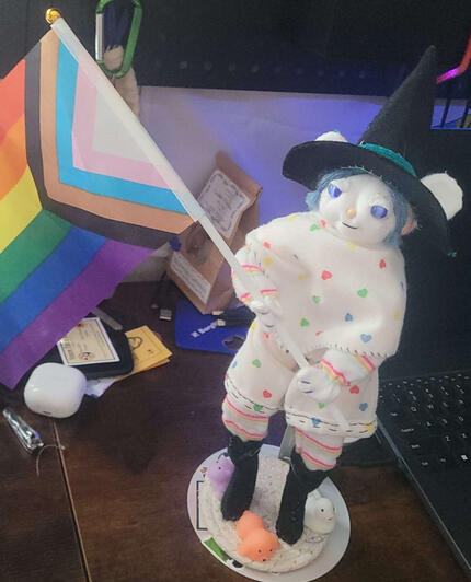 Circe the pride witch! This doll is mostly white with rainbow accents, star-sapphire style eyes, blue hair and a wooden bead nose.